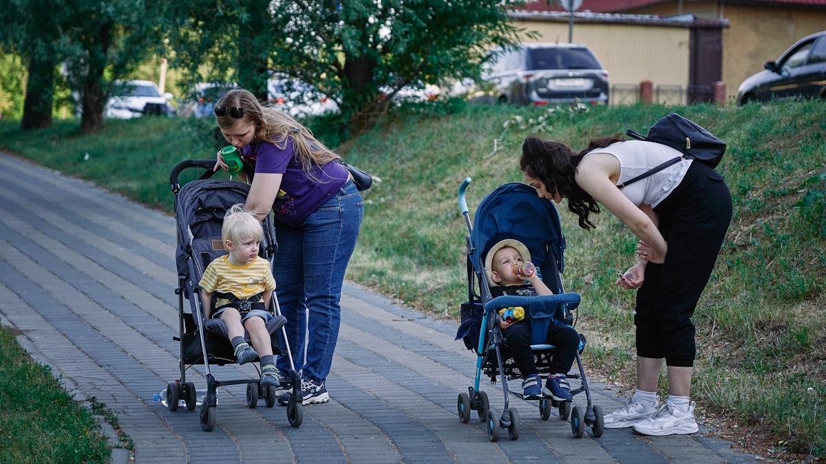 a woman pushing a stroller with two children in it
